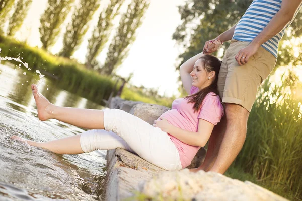 Casal grávida relaxante por lago — Fotografia de Stock