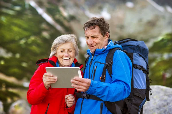 Pareja mayor usando mapa en la tableta — Foto de Stock