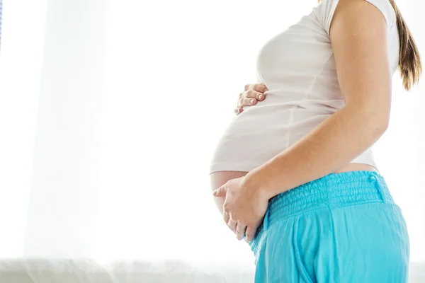 Mulher grávida com as mãos sobre a barriga — Fotografia de Stock