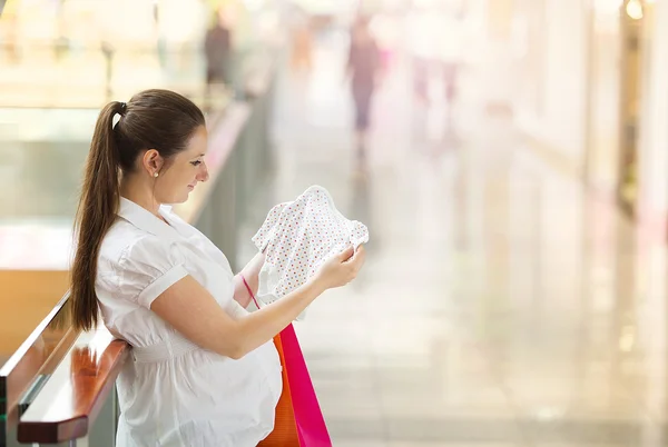 Woman looking at new baby clothes — Stock Photo, Image