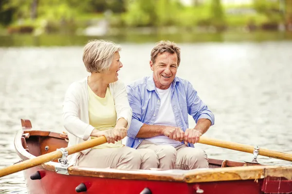 Seniorenpaar paddelt auf Boot — Stockfoto