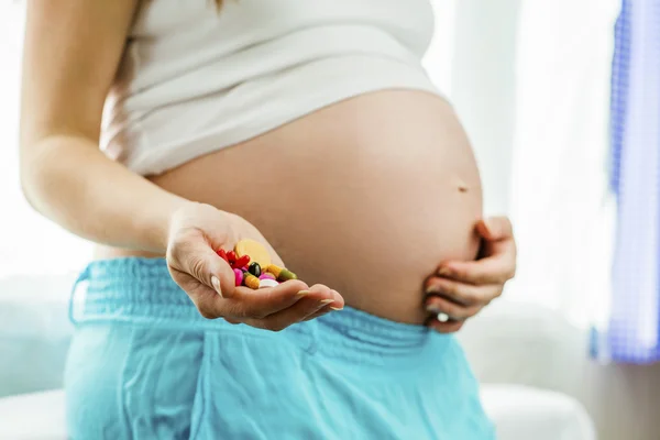 Mujer embarazada sosteniendo pastillas — Foto de Stock