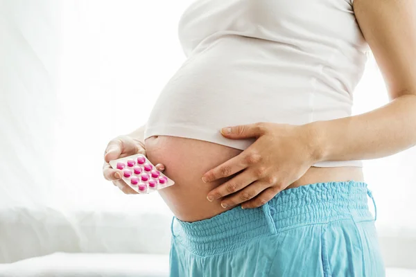 Mulher grávida segurando pílulas — Fotografia de Stock