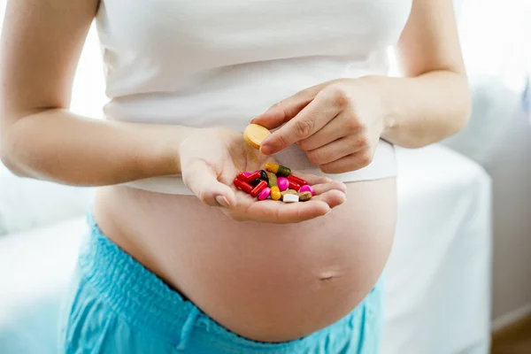 Pregnant woman holding pills — Stockfoto