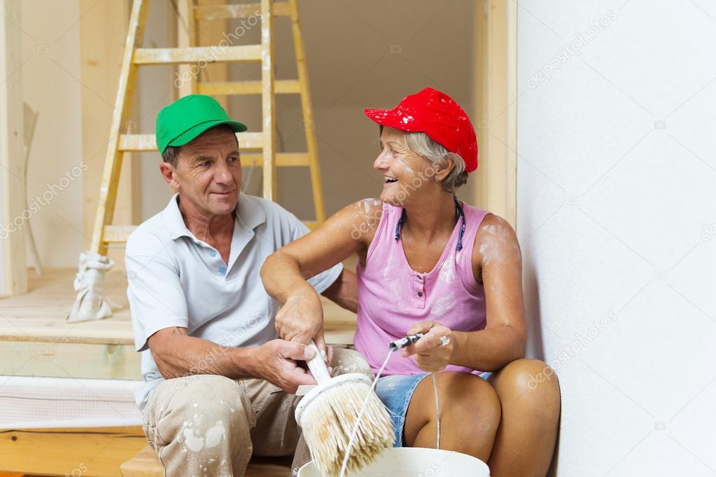 Senior couple painting wall with brush