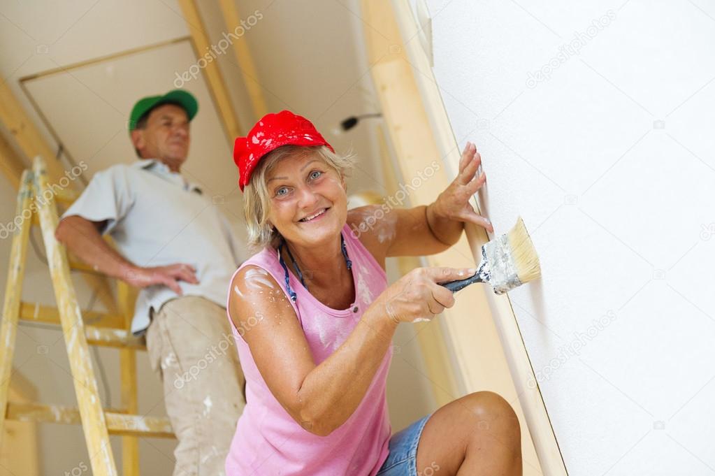 Senior couple painting wall with brush