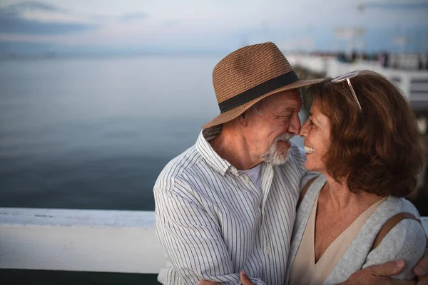 Porträt eines glücklichen, verliebten Senioren-Paares, das sich im Freien auf einem Steg am Meer umarmt, einander ansieht, Sommerurlaub. — Stockfoto