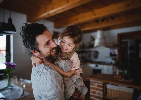 Padre maturo con la piccola figlia in piedi in casa, tenendo e abbracciando. — Foto Stock