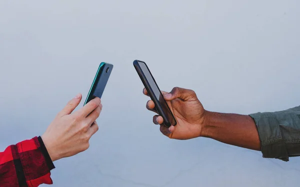 Gros plan de jeunes mains de couple biracial à l'aide de smartphones sur fond blanc — Photo