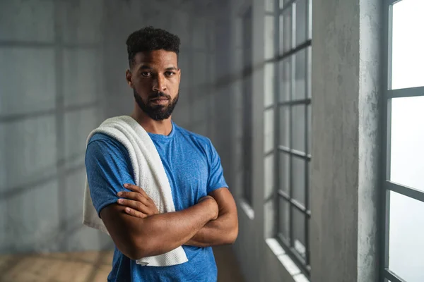 Молодой афроамериканский спортсмен, стоящий в помещении в тренажерном зале, смотрящий в камеру, концепция тренировок. — стоковое фото