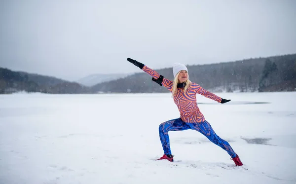 Kış aylarında açık havada esneme egzersizi yapan aktif kıdemli bir kadının ön görüntüsü.. — Stok fotoğraf