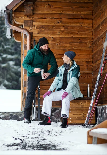 Reifes Paar rastet bei Holzhütte im Freien in winterlicher Natur, Langlauf. — Stockfoto