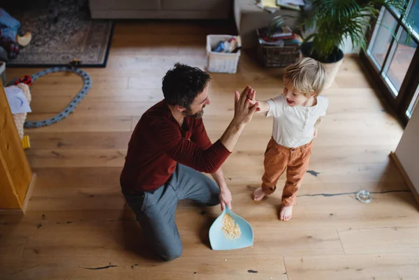 Hoher Blickwinkel auf Vater High Fiving mit kleinem Sohn nach dem Kehren zu Hause, tägliche Hausarbeit Konzept. — Stockfoto