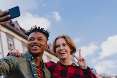 Şehirdeki sosyal ağlar için selfie çeken melez bir çiftin düşük açılı görüntüsü..