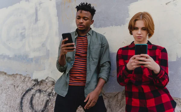 Jovem casal biracial viciado em smartphones ao ar livre na cidade, conceito de mídia social — Fotografia de Stock