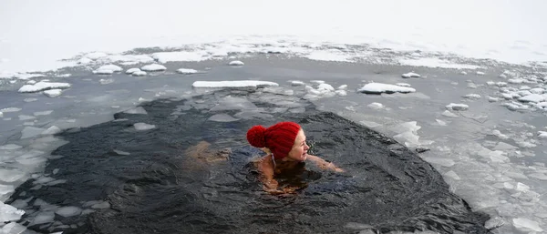 Aktywna seniorka pływająca w otworze wodnym w zamarzniętym jeziorze zimą, koncepcja zimnej terapii. — Zdjęcie stockowe