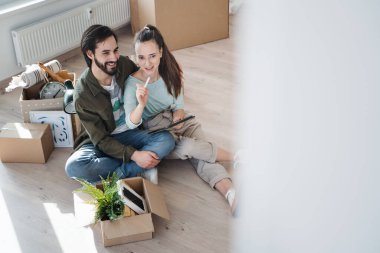 Tabletli genç çiftin yeni bir eve taşınma, yeni bir eve taşınma ve taşınma konseptini planlarken yüksek açılı görüntüsü..