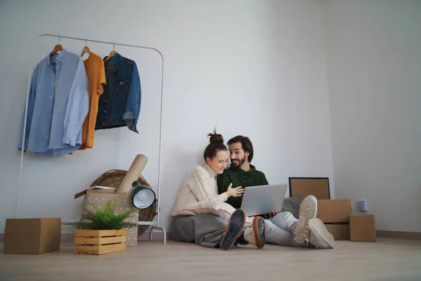 Jeune couple avec ordinateur portable assis sur le sol et la planification lors du déménagement dans un nouvel appartement, nouvelle maison et concept de relocalisation. — Photo