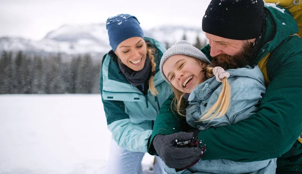 Сім'я з маленькою дочкою обіймається на відкритому повітрі в зимовій природі — стокове фото