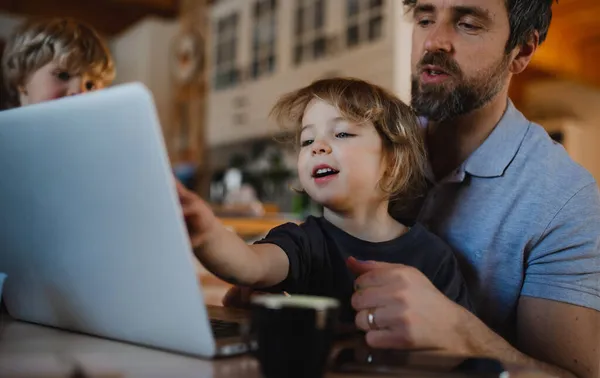 Medio padre adulto con niños pequeños que trabajan en el interior del hogar, concepto de oficina en casa. — Foto de Stock