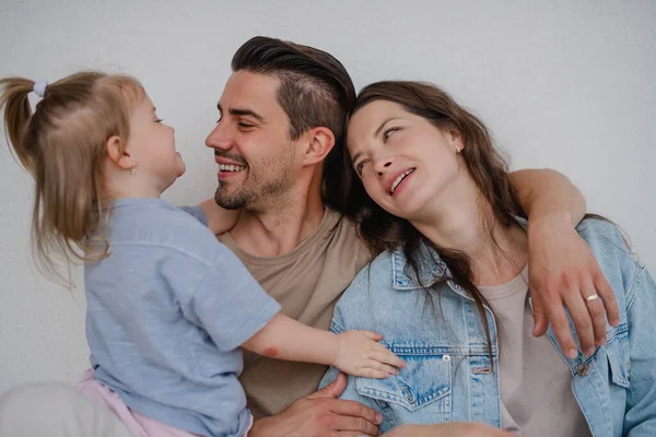 Portret van gelukkige jonge ouders met kleine dochter knuffelen op witte achtergrond. — Stockfoto