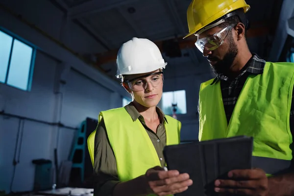 Low angle view of industrial inspectors with tablet doing a general check up and talking indoors at metal workshop. — Stock Photo, Image