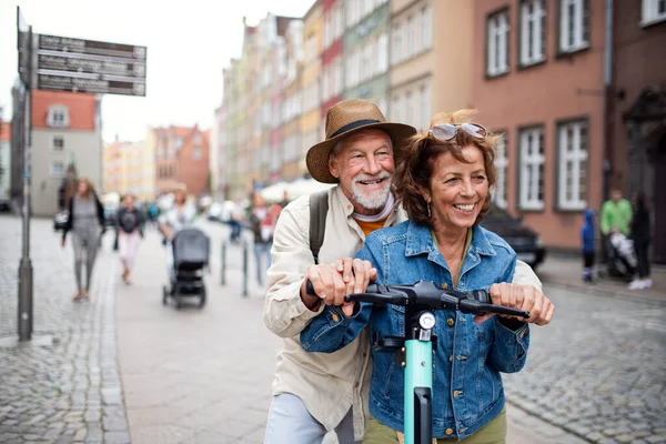 町で一緒に屋外スクーターに乗る幸せなシニアカップル観光客の肖像画 — ストック写真