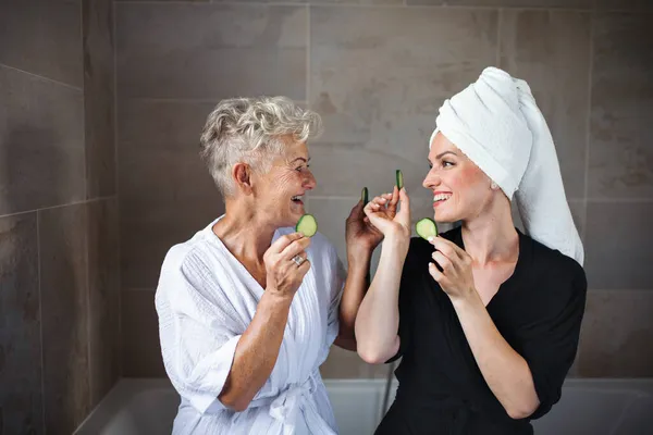 Glückliche Seniorin im Bademantel mit erwachsener Tochter zu Hause, Selfcare-Konzept. — Stockfoto