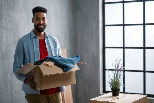 Happy young man holding packing boxes moving home, looking at camera, new living concept. — Stock Photo, Image
