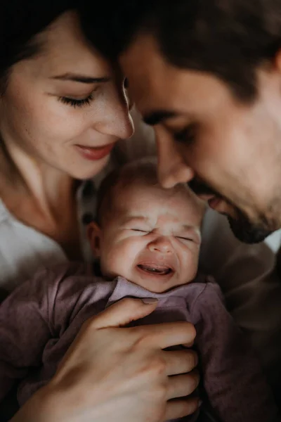 Close up de pais jovens segurando e beijando seu bebê recém-nascido dentro de casa — Fotografia de Stock