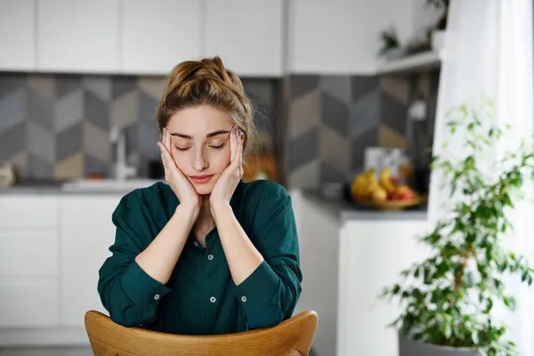 Portrét unavené mladé studentky sedící a relaxující se zavřenýma očima v kuchyni. — Stock fotografie