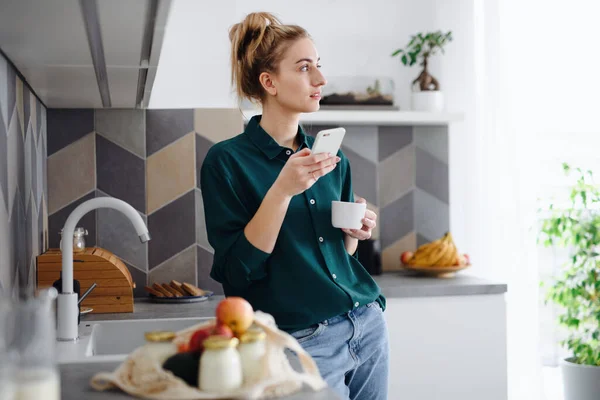Retrato de estudiante joven con café en casa, usando smartphone. —  Fotos de Stock