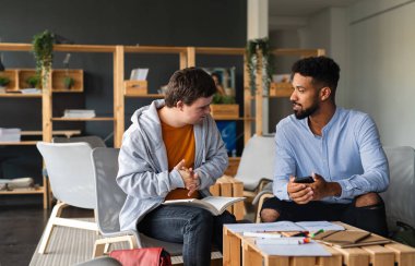 Down sendromlu genç ve mutlu bir adam ve özel öğretmeni okulda ders çalışıyor..