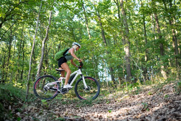 森の中でアクティブなシニア女性バイカーサイクリング屋外の低角度ビュー. — ストック写真