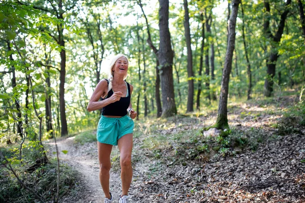 Feliz ativa mulher sênior correndo ao ar livre na floresta. — Fotografia de Stock
