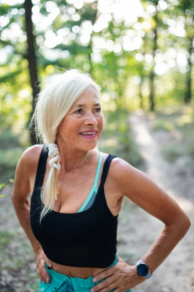 Porträt einer aktiven Seniorin, die draußen im Wald steht. — Stockfoto