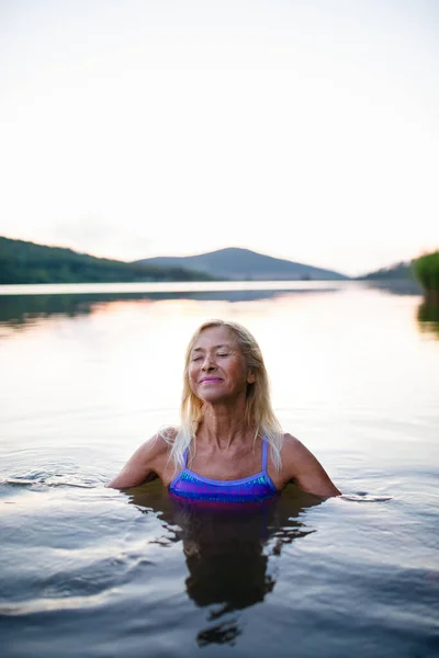 Portret van een actieve senior zwemmer die buiten in het meer duikt. — Stockfoto