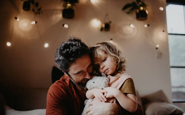 Зрілий батько з сумною маленькою дочкою обіймає в приміщенні вдома . — стокове фото