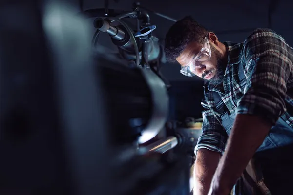 Close up of young concentrated african american industrial man working on cutter in metal workshop. — Stock Photo, Image