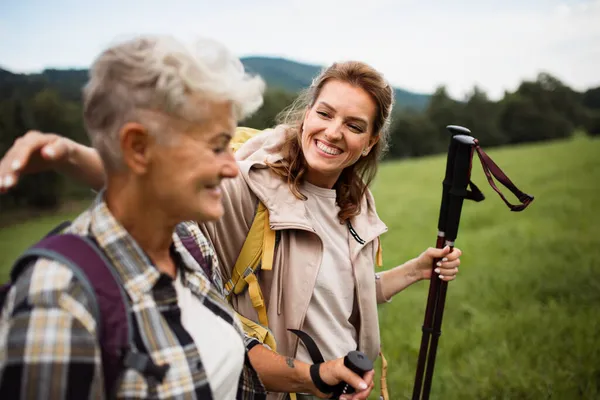 Heureuse femme moyenne adulte avec des bâtons de trekking randonnée avec mère aînée active en plein air dans la nature. — Photo