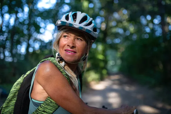 Portret aktywnej starszej pani rowerzystki jeżdżącej na rowerze po lesie. — Zdjęcie stockowe