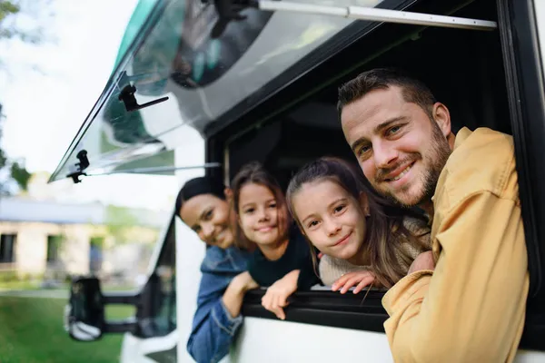 Glückliche junge Familie mit zwei Kindern schaut aus dem Wohnwagenfenster. — Stockfoto