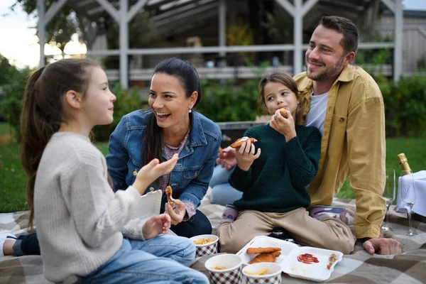 Keluarga muda yang bahagia duduk di atas selimut dan pergi piknik di luar ruangan di daerah restoran. — Stok Foto