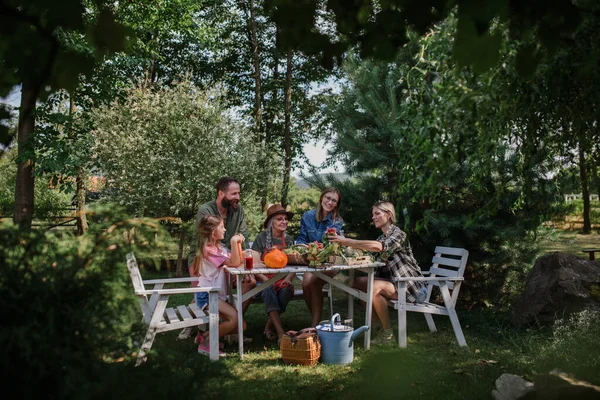 Bauernfamilie sitzt am Tisch und betrachtet ihre Ernte im Freien auf dem Bauernhof der Gemeinde. — Stockfoto