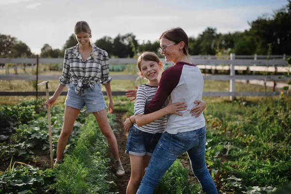 Happy little girl with mother hugging outdoors at community farm. — Stock Photo, Image