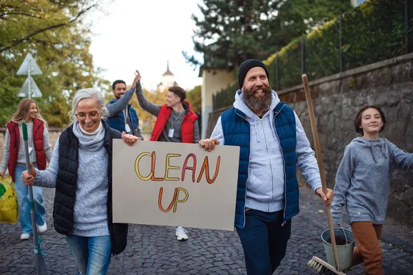 Diversi gruppi di volontari felici che camminano con banner e strumenti per pulire le strade. — Foto Stock