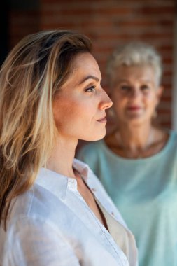 Kıdemli anne evde yetişkin kızına bakıyor. Önplandaki kadına seçici odaklanma.