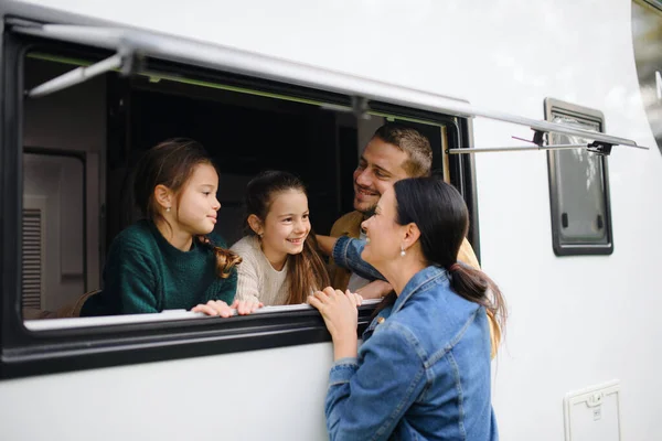 Šťastné dvě malé holčičky s otcem dívají z okna karavany a mluví s matkou. — Stock fotografie