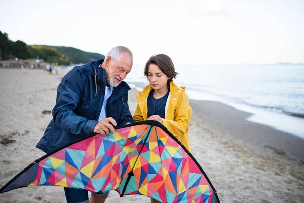 Älterer Mann und seine Enkelin bereiten Drachen für das Fliegen am Sandstrand vor. — Stockfoto