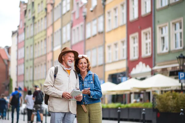 Portrét šťastných seniorů pár turistů pomocí mapy a smartphone venku ve městě ulici — Stock fotografie